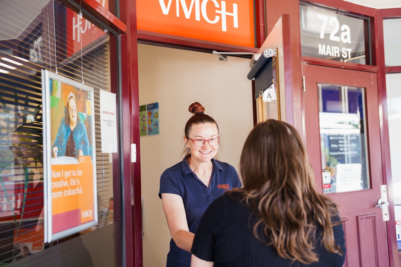 A woman opening the door and welcoming another woman in.