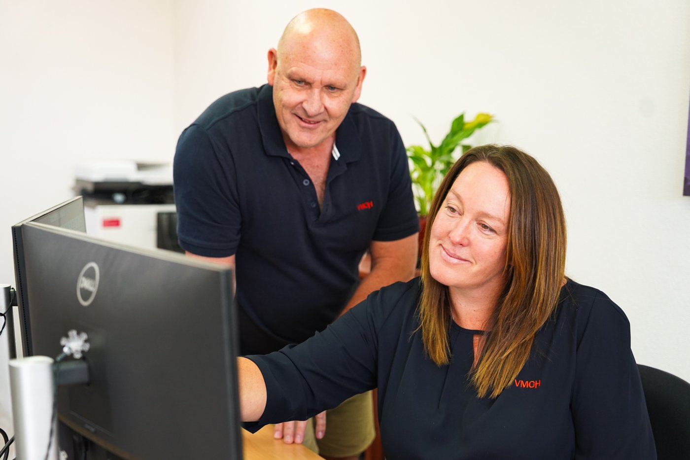 A woman pointing at her computer monitor, sharing information with her coworker.