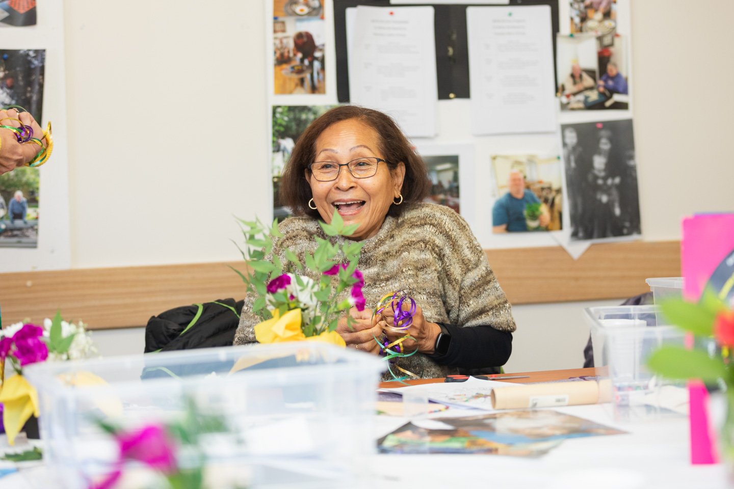 A woman laughing while making a bouquet.