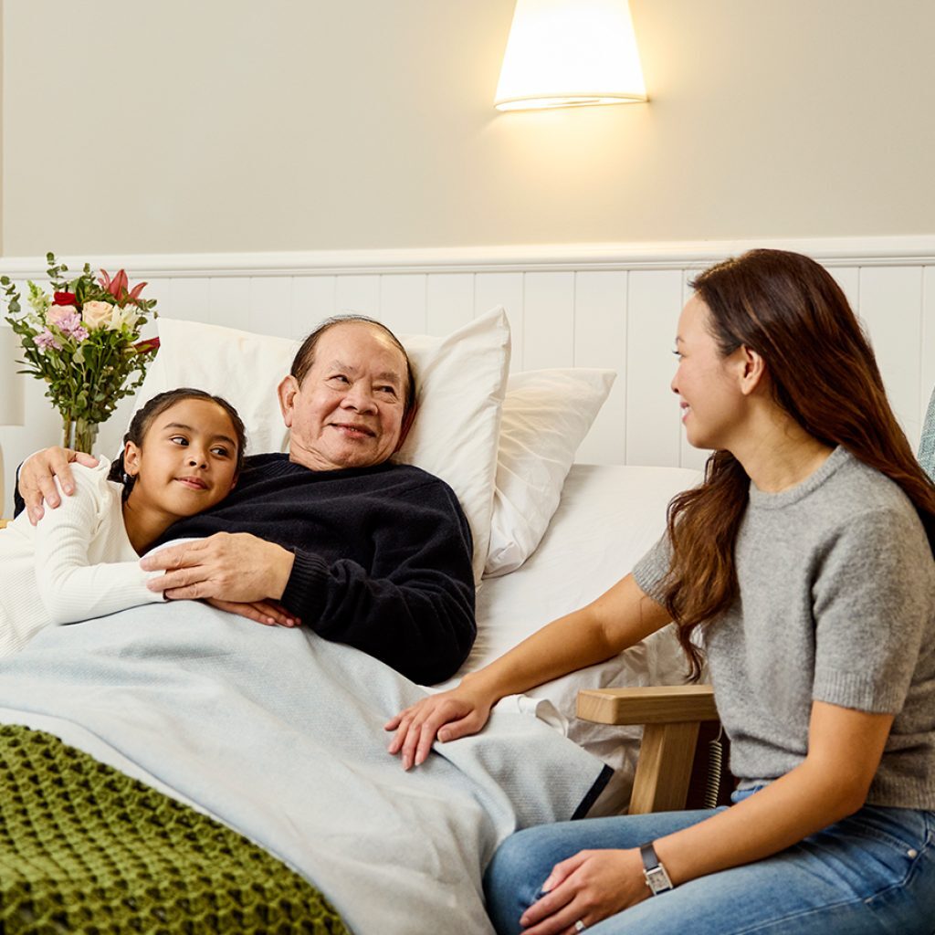 A man in bed surrounded by child and woman.