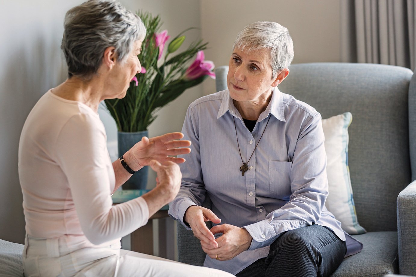 An elderly woman sitting and talking with a pastoral care worker