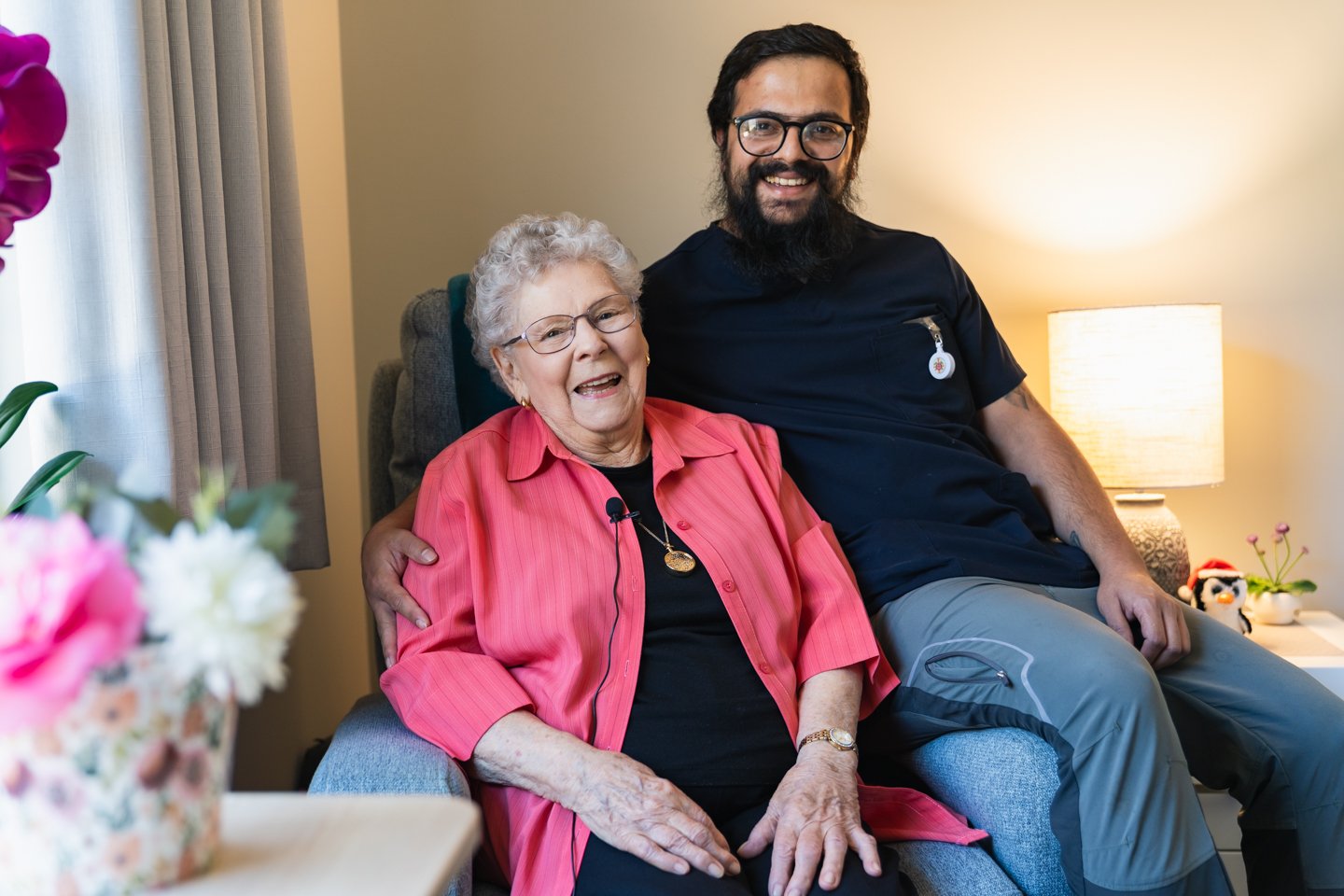 An aged care worker with their arm around a resident smiling