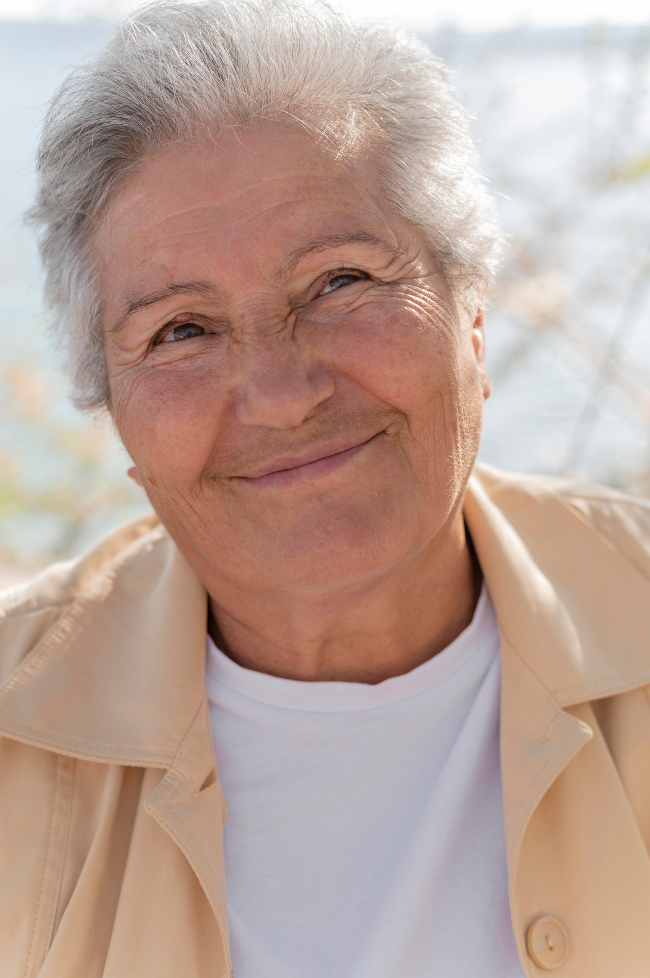 A white haired woman in a tan jacket.